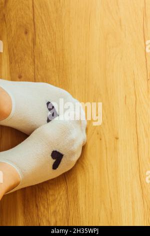 Jambes en chaussettes courtes sur fond de bois clair. Banque D'Images