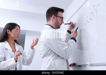 Deux chercheurs odontologues étudient l'anatomie dentaire sur un tableau blanc. Banque D'Images