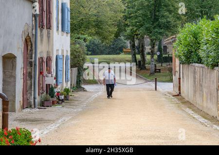 Un prêtre marchant dans la rue du petit village Labastide d'Armagnac, dans le sud de la France Banque D'Images