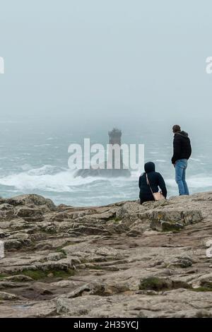 Plogoff (Bretagne, nord-ouest de la France) : couple face à la mer et au phare de la Vieille sur la pointe du raz, par une journée de tempête Banque D'Images