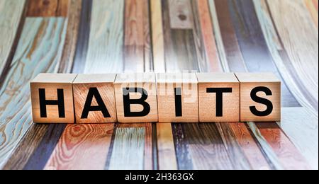 Le mot habitudes est écrit sur des cubes en bois qui se trouvent sur un fond coloré Banque D'Images