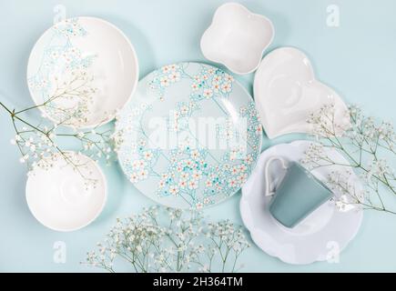 Printemps créativité festive composition de beaucoup de beau vaisselle blanc et avec décor floral et fleurs blanches sur fond bleu clair.Vue de dessus.FLA Banque D'Images