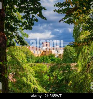 Nature et environnement à Lucca.Vue sur les vieux bâtiments du centre historique à travers des branches d'arbres avec des feuilles vertes et jaunes Banque D'Images