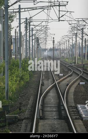 Cluj-Napoca, Roumanie, 7 juin 2009: Les voies ferrées convergentes vont jusqu'à un point de fuite à l'horizon avec des pôles de tension le long du côté. Banque D'Images