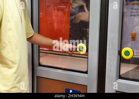 Homme appuyant sur le bouton pour ouvrir une porte de voiture de métro Banque D'Images