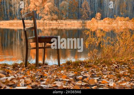 Une ancienne chaise en bois se trouve sur la rive du lac Banque D'Images