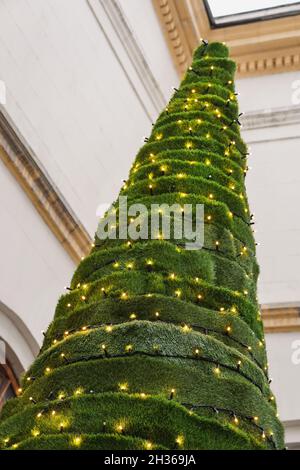 Arbre de Noël inhabituel en herbe artificielle décoré de guirlandes dorées.Mise au point sélective. Banque D'Images