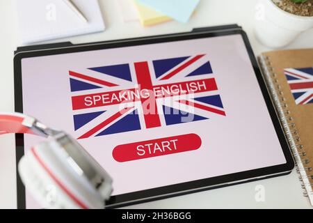 Écouteurs couchés sur une tablette numérique pour l'enseignement de l'anglais en gros plan.Cours en ligne pour l'apprentissage des langues étrangères concept Banque D'Images
