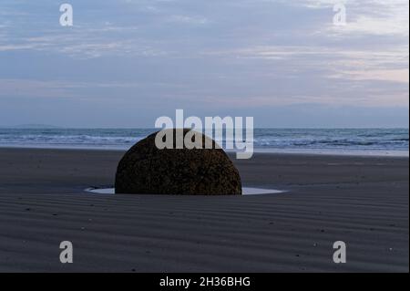 Le lever du soleil colore le ciel au-dessus de Moeraki Boulders dans l'île du Sud de la Nouvelle-Zélande Banque D'Images