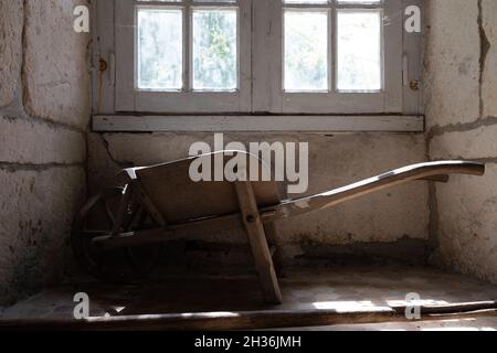 Vieille brouette dans une pièce rurale sous la fenêtre Banque D'Images