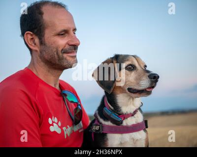 Homme tenant son chien dans le parc avec le ciel sur le fond Banque D'Images
