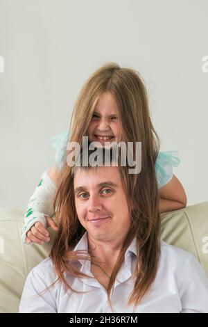 Père et sa fille s'amusent dans leur salon. Petite fille ont la main blessée mais elle est heureuse être ensemble son père. Banque D'Images