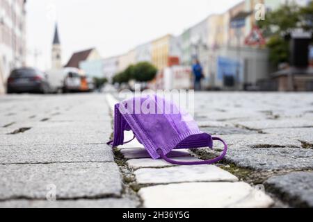 26 octobre 2021, Bavière, Mühldorf am Inn: Un masque médical violet se trouve sur une rue, tandis que la vieille ville de Mühldorf am Inn peut être vue en arrière-plan.Le Mühldorf am Inn est actuellement l'une des régions bavaroises les plus touchées par Corona.Photo: Matthias balk/dpa Banque D'Images