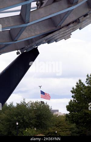 Un drapeau américain vu à travers le Unisphere dans le parc Corona de Flushing Meadows à Queens, New York. Banque D'Images