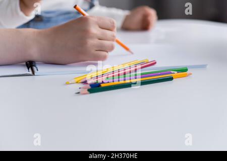 Vue rognée d'une femme qui dessine près d'un enfant flou et crayons de couleur sur une table Banque D'Images