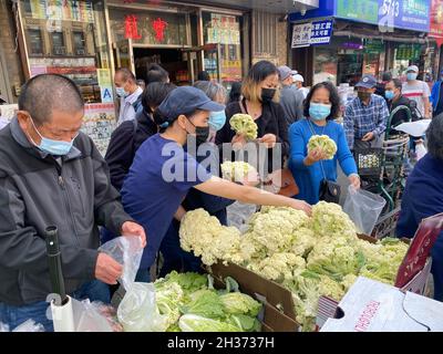 Les amateurs de shopping profitent du chou-fleur frais et d'autres légumes en vente sur le trottoir d'un marché de produits locaux dans le quartier de Chinatown, le long de la 8th Avenue dans le quartier de Sunset Park à Brooklyn, New York. Banque D'Images