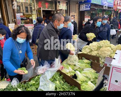 Les amateurs de shopping profitent du chou-fleur frais et d'autres légumes en vente sur le trottoir d'un marché de produits locaux dans le quartier de Chinatown, le long de la 8th Avenue dans le quartier de Sunset Park à Brooklyn, New York. Banque D'Images