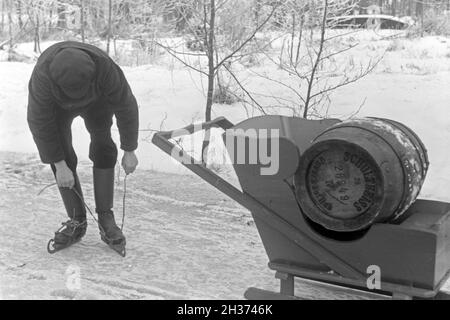 Schnallt Schlittschuhkufen sich ein Mann, une um mit dem Schlitten ein Fass Pils Schultheiss zu transportieren im Spreewald, Deutschland 1930 er Jahre. Mettre un homme sur son patin porteur à Spreewalad zone afin de transporter le baril de bière Schultheiss, Allemagne 1930. Banque D'Images