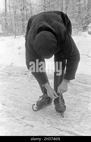 Schnallt Schlittschuhkufen Ein Mann sich im Spreewald, Deutschland 1930 er Jahre. Mettre un homme sur son patin porteur à Spreewalad salon, Allemagne 1930. Banque D'Images
