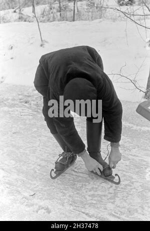 Schnallt Schlittschuhkufen Ein Mann sich im Spreewald, Deutschland 1930 er Jahre. Mettre un homme sur son patin porteur à Spreewalad salon, Allemagne 1930. Banque D'Images