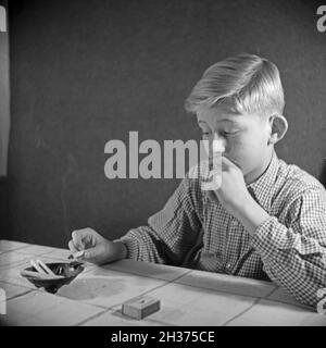 Série: Ein neugieriger Junge probiert seine erste Zigarette, Deutschland 1940er Jahre.Un curieux garçon essayant sa première cigarette, Allemagne des années 1940. Banque D'Images