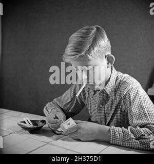 Série: Ein neugieriger Junge probiert seine erste Zigarette, Deutschland 1940er Jahre.Un curieux garçon essayant sa première cigarette, Allemagne des années 1940. Banque D'Images