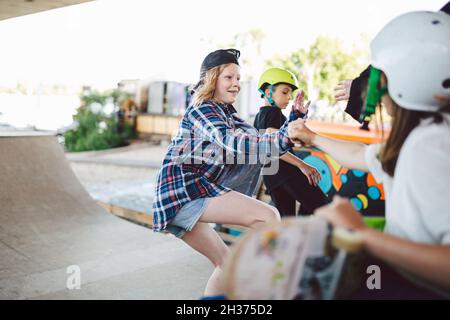 Garçons filles amis ont le plaisir ensemble hurler pendant l'entraînement de skateboard, de l'équitation et de faire des tours sur demi-pipe dans le parc de skate.Jeunes, ensemble et Banque D'Images