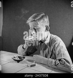 Série: Ein neugieriger Junge probiert seine erste Zigarette, Deutschland 1940er Jahre.Un curieux garçon essayant sa première cigarette, Allemagne des années 1940. Banque D'Images