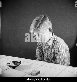 Série: Ein neugieriger Junge probiert seine erste Zigarette, Deutschland 1940er Jahre.Un curieux garçon essayant sa première cigarette, Allemagne des années 1940. Banque D'Images