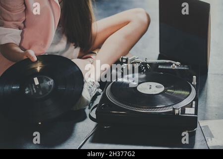 Les mains des femmes utilisent un lecteur de vinyle rétro sur fond bleu rose pastel.DJ.Vue de dessus Banque D'Images