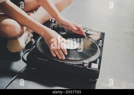 Une jeune femme s'assoit sur le sol et explore les disques vinyles, les met sur un joueur rétro. Banque D'Images