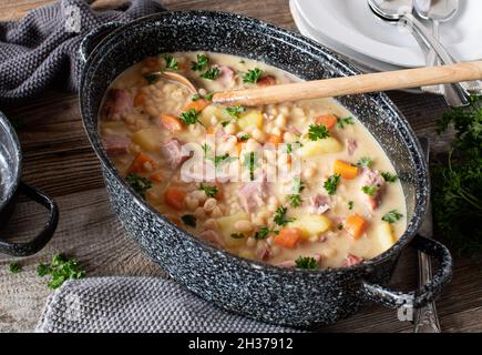 Ragoût rustique avec haricots blancs, viande de porc fumée, légumes-racines et pommes de terre.Servi dans un ragoût sur une table en bois d'en haut Banque D'Images