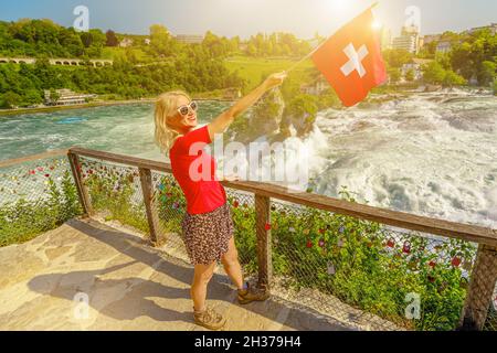 Gros plan d'une femme suisse avec drapeau suisse au coucher du soleil.Vue aérienne des chutes du Rhin en Suisse.La plus puissante et la plus grande cascade de Banque D'Images