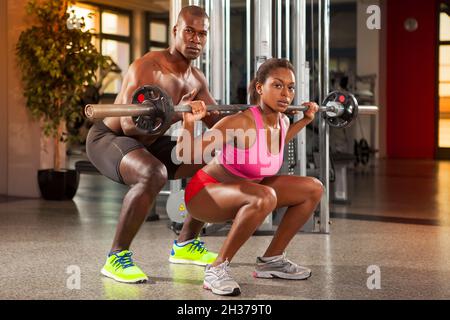 un couple noir musclé s'entraîne dans la salle de gym sur des appareils de fitness Banque D'Images