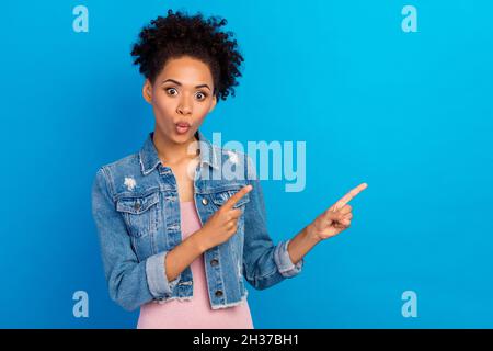 Photo de jeune Funky afro american femme point doigt vide espace vente nouvelles isolées sur fond bleu Banque D'Images