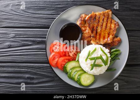 Plats vietnamiens brisés de riz avec du porc grillé et des légumes frais en gros plan dans une assiette sur la table. Vue horizontale du dessus Banque D'Images