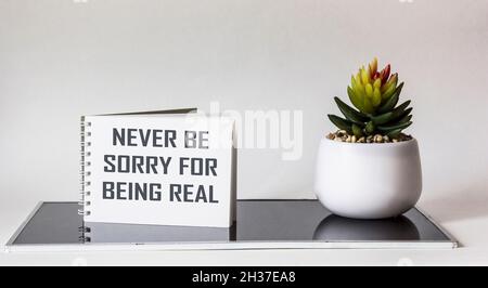 Je ne regrette jamais d'être réel.Phrase inspirante sur le bloc-notes, à côté d'une fleur de cactus sur fond blanc et noir.Concept de développement personnel Banque D'Images