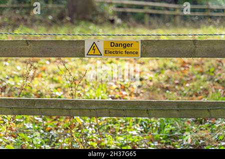 Panneau jaune danger de clôture électrique sur une clôture en bois et en métal Banque D'Images