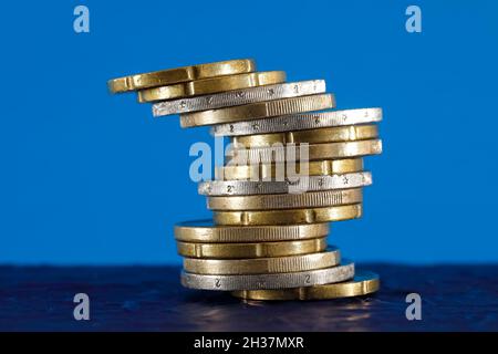 La pile instable de pièces en euros est sur fond bleu.La surface sur laquelle ces pièces sont placées est bleu foncé. Banque D'Images