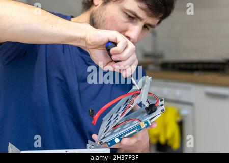 Le jeune homme assemble les composants électroniques de l'ordinateur avec ses propres mains.Passe-temps, technicien, assemblage de bricolage et invention de la technologie Banque D'Images