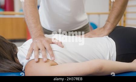 Mains du physiothérapeute faisant un massage médical du dos, à une patiente, pendant un traitement de réadaptation. Banque D'Images