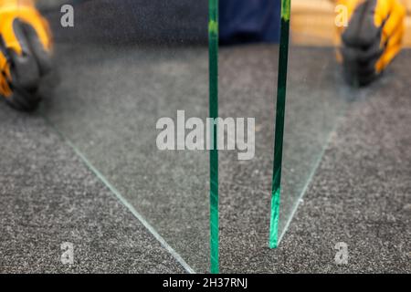 un ouvrier dans une usine de verre tient deux morceaux de verre dans ses mains Banque D'Images