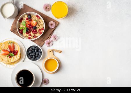 Petit déjeuner servi le matin : crêpes, porridge, fromage cottage, granola, muesli,jus d'orange, thé, café, fruits et baies. Banque D'Images