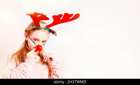 Petite fille dans un masque de Noël sur un fond clair, foyer doux.Cristmas concept.Masques de nouvel an.Une petite fille avec des points de cornes de Noël . Banque D'Images