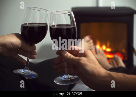 Couple assis dans une chambre confortable avec cheminée sur un canapé avec des verres de vin.Concept de famille et d'amour Banque D'Images