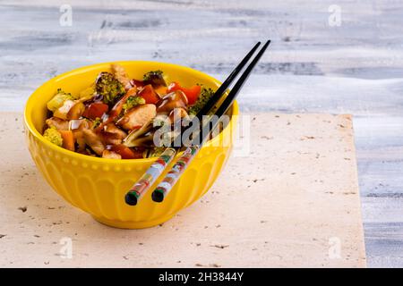 poulet yakissoba dans un bol jaune. Banque D'Images