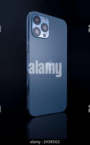 Galati, Roumanie - 14 octobre 2021: Studio de photo de la nouvelle Apple iPhone 12 Pro Max bleu, vue arrière avec logo Apple.Isoler sur le fond de verre noir Banque D'Images