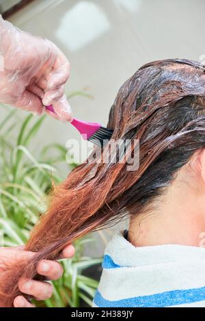 Gros plan d'un mari colorant les cheveux de sa femme à la maison. Banque D'Images