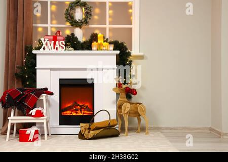 Cheminée avec cerf en bois et bois de chauffage dans la chambre décorée pour Noël Banque D'Images