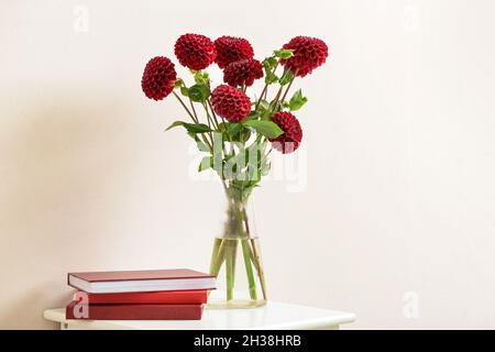 Vase avec dahlias et blocs-notes sur table avec fond de couleur Banque D'Images